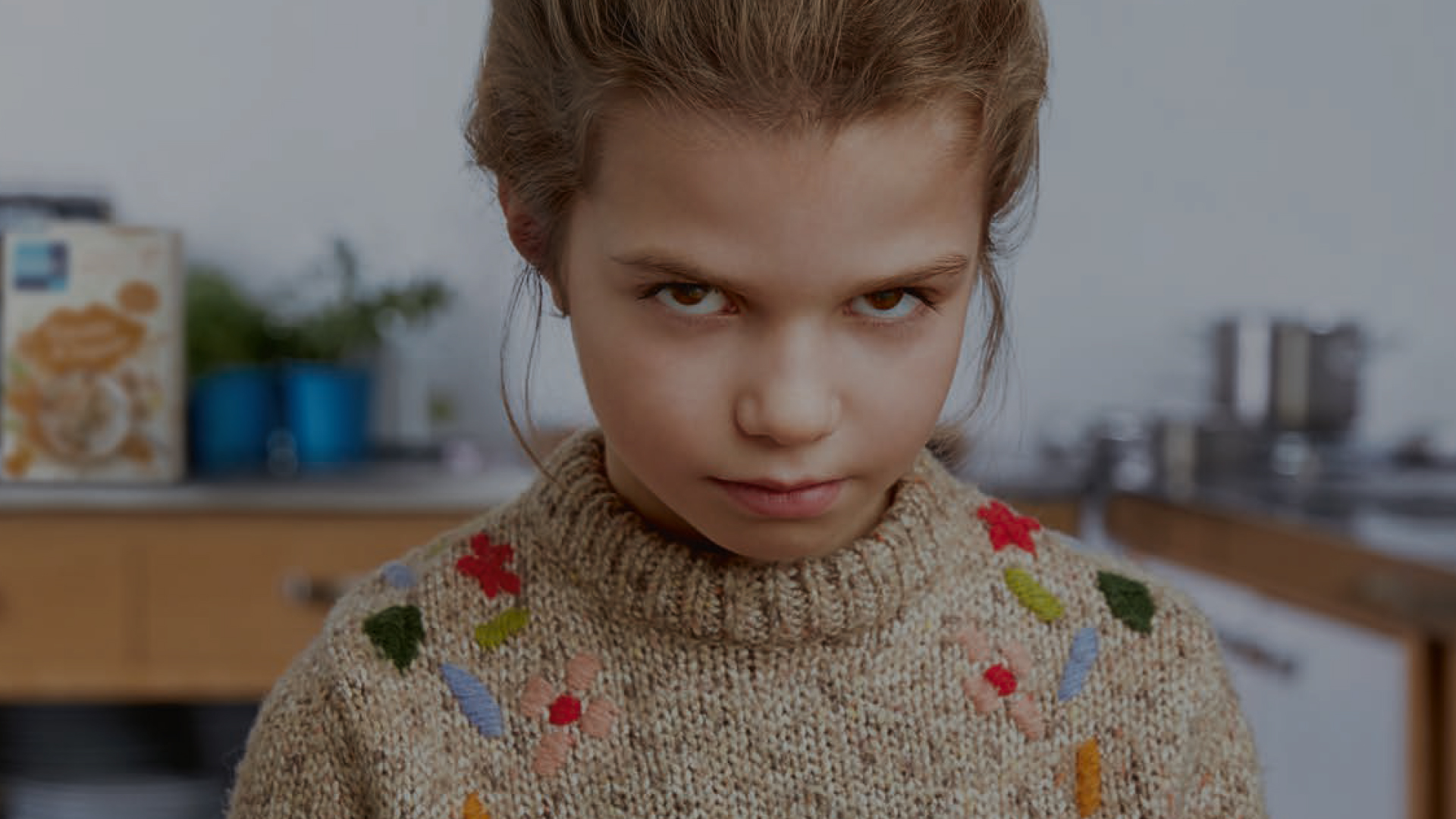 Girl with blonde hair and brown eyes is looking grumpy into the camera