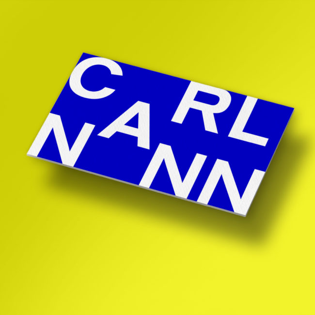 white CarlNann Logo on blue square in front of yellow background