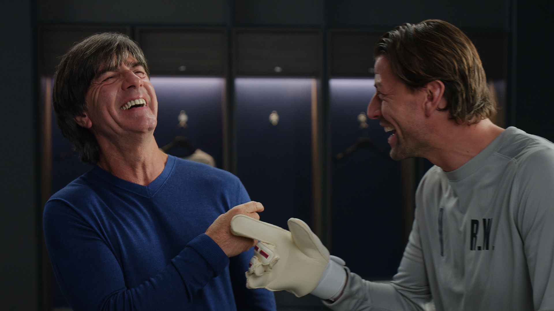 Coach and soccer player inside the changing room, both look at each other and are laughing