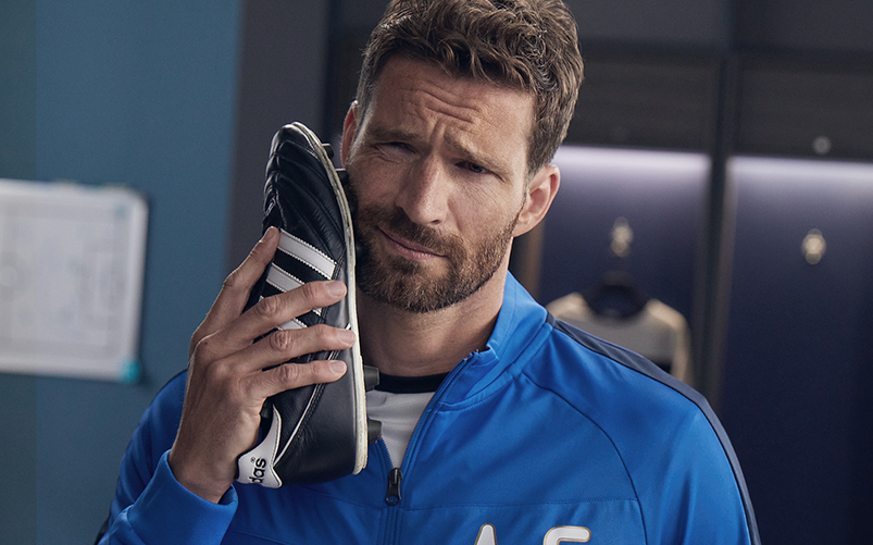 Soccer player is holding soccer shoe against his face