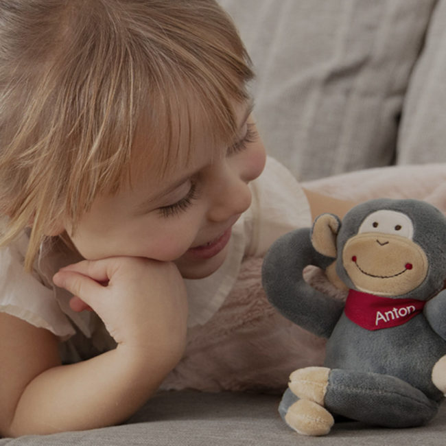 Blonde girl is playing with stuffed animal Anton on the sofa