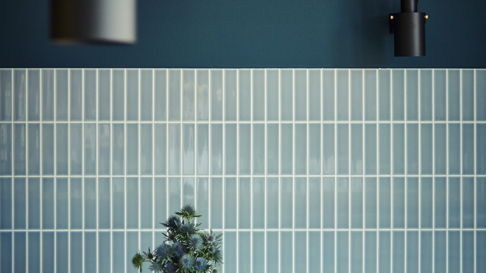 Flowers in front of blue tiles and a socket