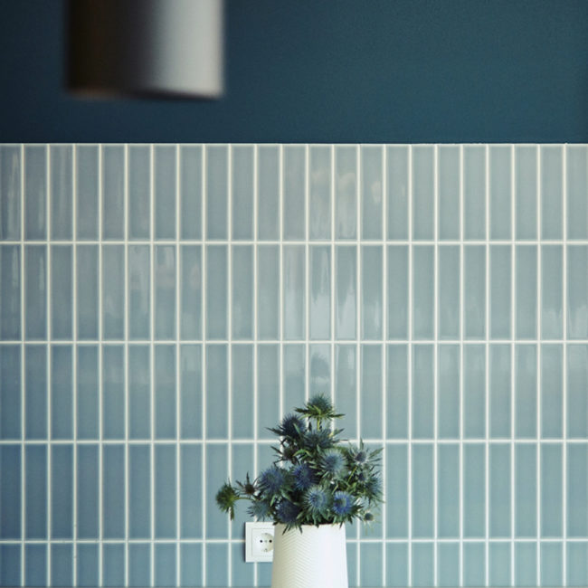 Flowers in front of blue tiles and a socket