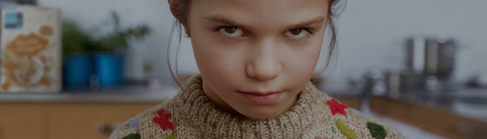 Girl with blonde hair and brown eyes is looking grumpy into the camera